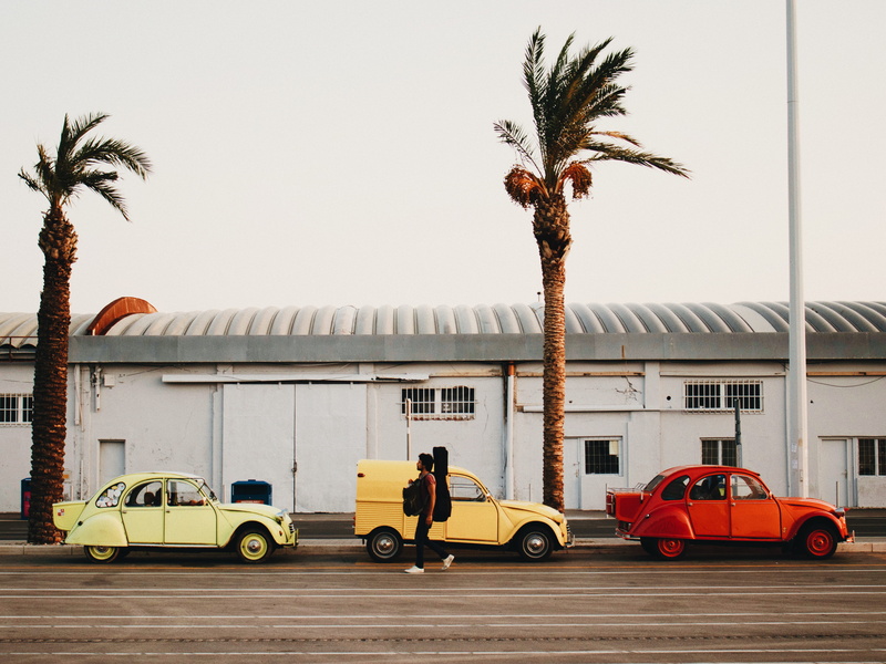 walking, yellow, streetscape, building, tropical climate, sky, vintage car, day, street, vehicles, mode of transportation, three, tree, cars, built structure