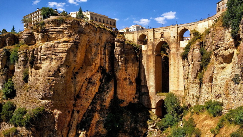 sunlight, sky, travel destinations, ancient, old, puente nuevo, building, bridge, ruined, old ruin, day, city, rocks, plant, building exterior, outdoors