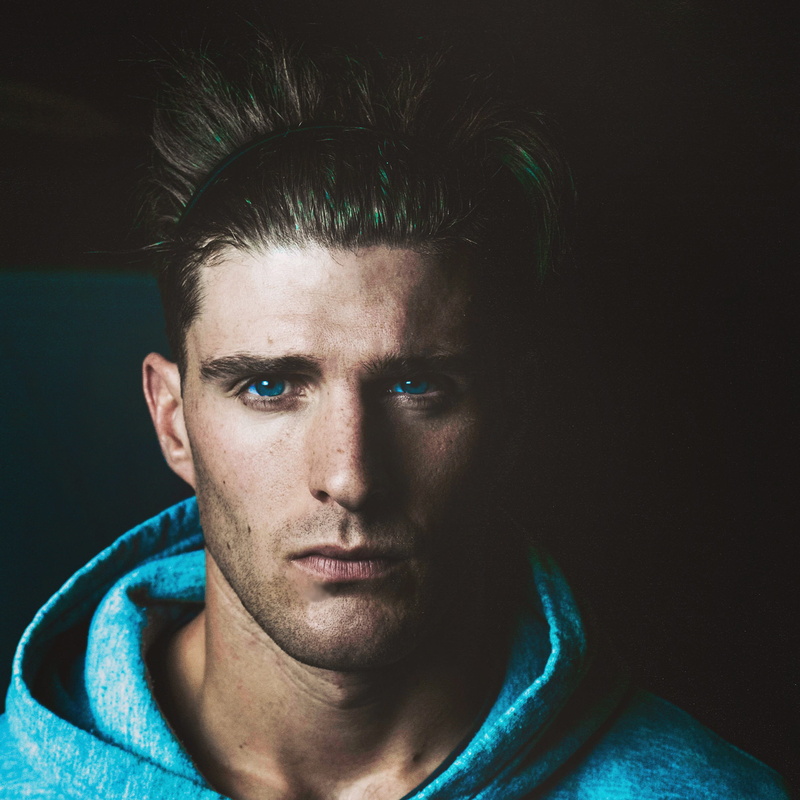 blue eyes, teal, one person, beard, black hair, indoors, blue, portrait, contemplation, caucasian, serious, handsome, close up, black background, beautiful people