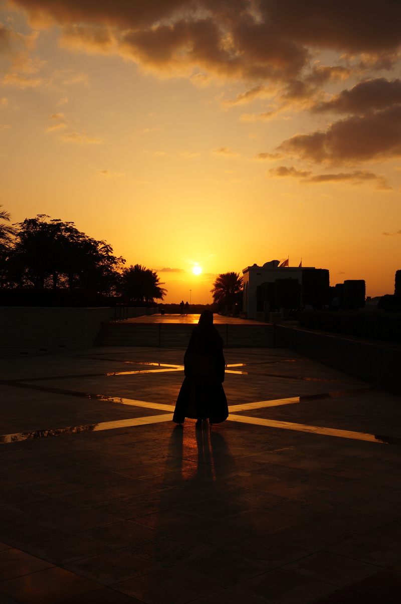 sunlight, rear view, built structure, abu dhabi, full length, real people, mosque, silhouette, one person, transportation, lifestyles, city, outdoors, woman