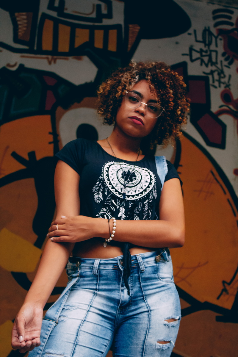 wall - building feature, facial expression, top, jeans, portrait, black, wearing, real people, pose, wall, fashion, woman, lifestyles, street photo, wear