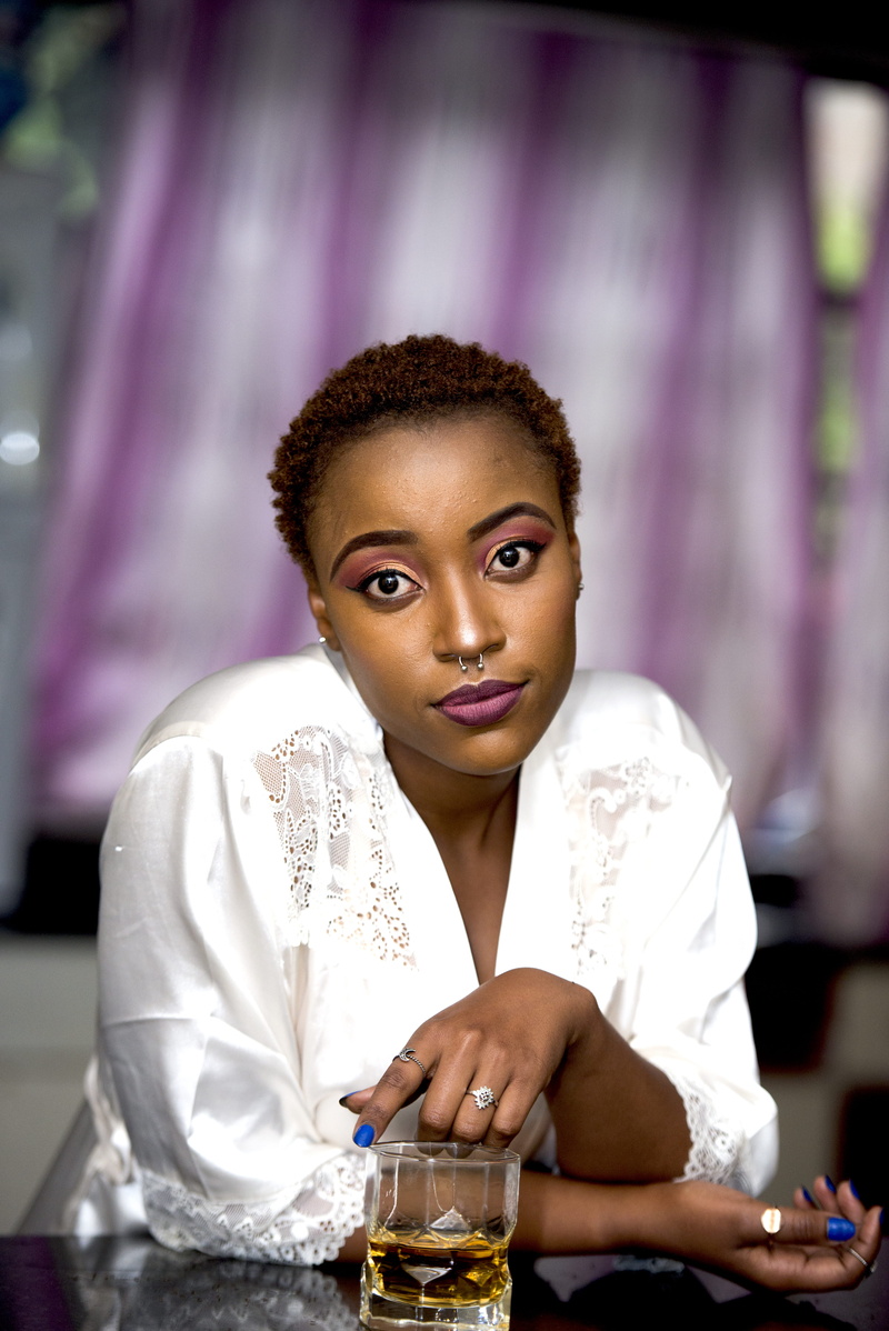 brown eyes, ring, black woman, waist up, focus on foreground, malo, indoors, beautiful woman, nose piercing, one person, selective, women, holding, wearing