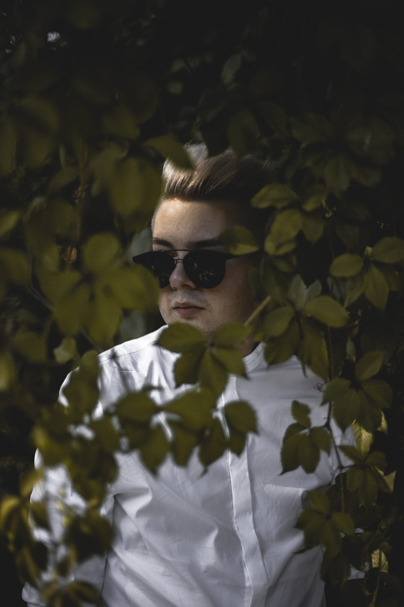 young adult, blur, plant, front view, light, fall, behind, wear, sunglasses, white shirt, leaves, person, leaf, fashion, from behind, headshot, man, glasses