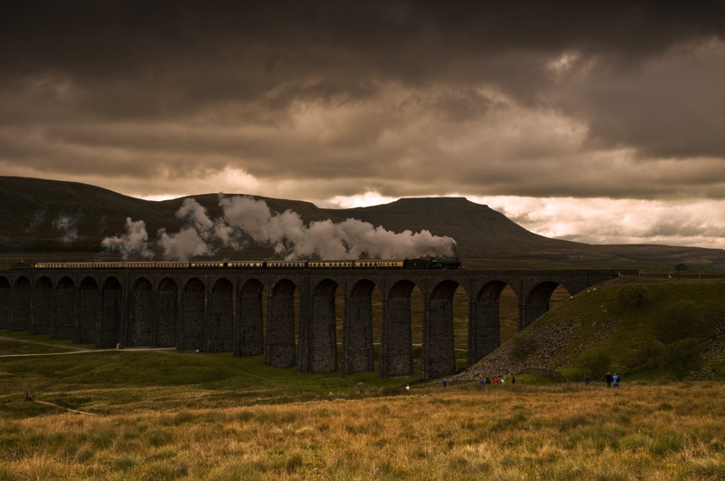 sky, arch bridge, light, grass, history, outdoors, architecture, environment, clouds, mountain, sunset, view, daylight, travel destinations, bridge - man made structure