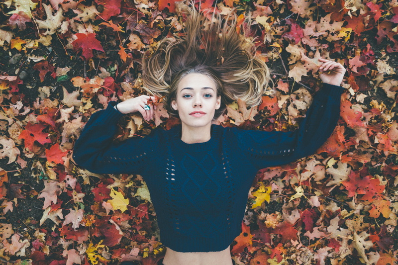 looking at viewer, lying on back, 1080P, blonde, Zach Allia, women, blue sweater, blue eyes, arms up, leaves