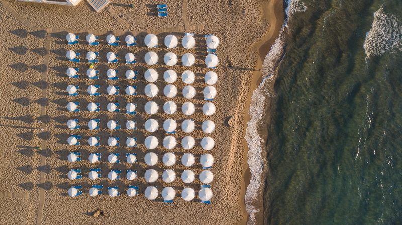 in a row, land, parasol, white, sea, patio, repetition, umbrella, ocean, aerial view, drone, no people, outdoors, nature, lot, side by side, high angle view