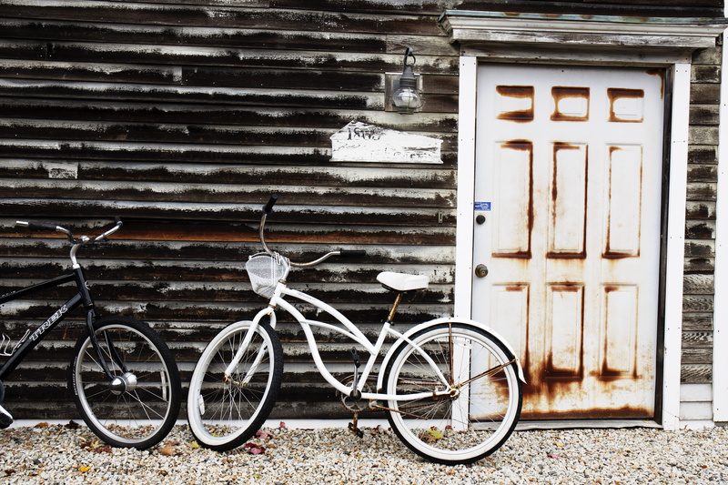 parking, day, road, dirt road, parked, machine, entrance, wooden, wall, built structure, outdoors, beside, bicycle, closed, stationary, path, architecture