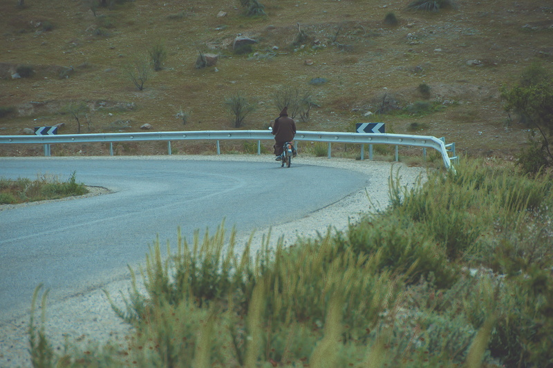 day, lifestyles, sign, slope, riding, promontory, outdoors, one animal, asphalt, nature, full length, transportation, human, highway, plant, bicycle, road