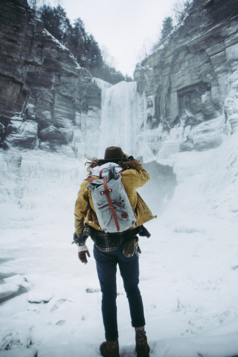 people, frozen, rock, white, hiking, jacket, day, clothing, carrying, winter, surrounded, near, waterfalls, cold temperature, trees, warm clothing, standing