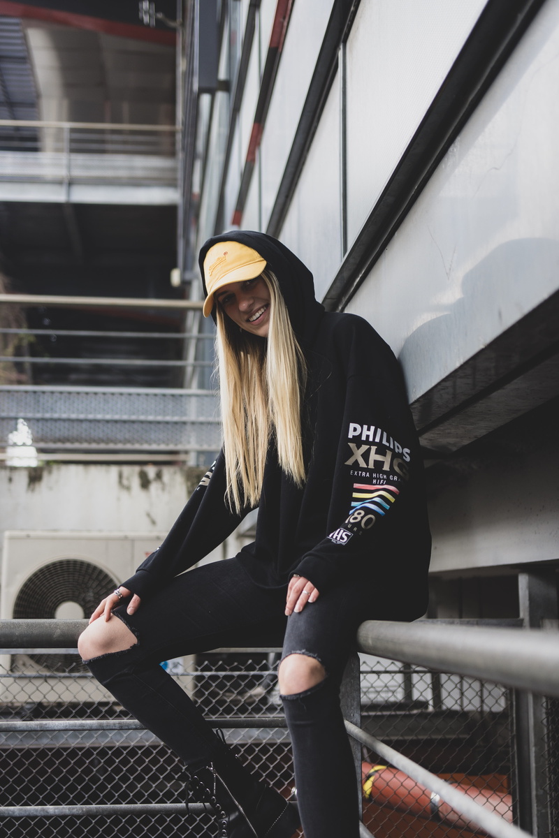 running shoe, women, clothing, front view, sitting, built structure, railing, hoodie, three quarter length, person, hood, overcoat, real people, human