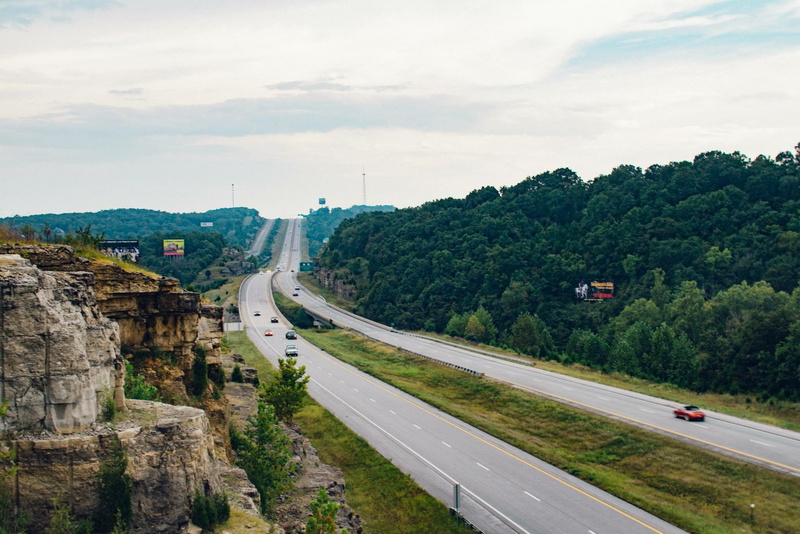 mountain, car, no people, nature, vehicle, trees, built structure, highway, cliff, near, transportation, trip, city, cloud - sky, sky, range, grass, cloud