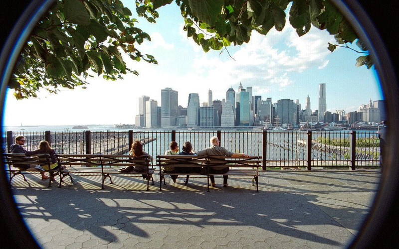 skyscraper, day, nature, sunlight, leisure activity, outdoors, USA, seat, group of people, building exterior, water, tree, cityscape, sky, benches, Brooklyn Heights Promenade