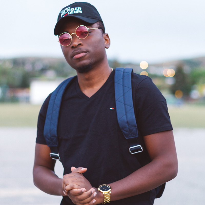 canada, standing, brand, gold, real people, front view, 2K, city, focus on foreground, waist up, outdoors, day, one person, casual clothing, ebony, expressive faces