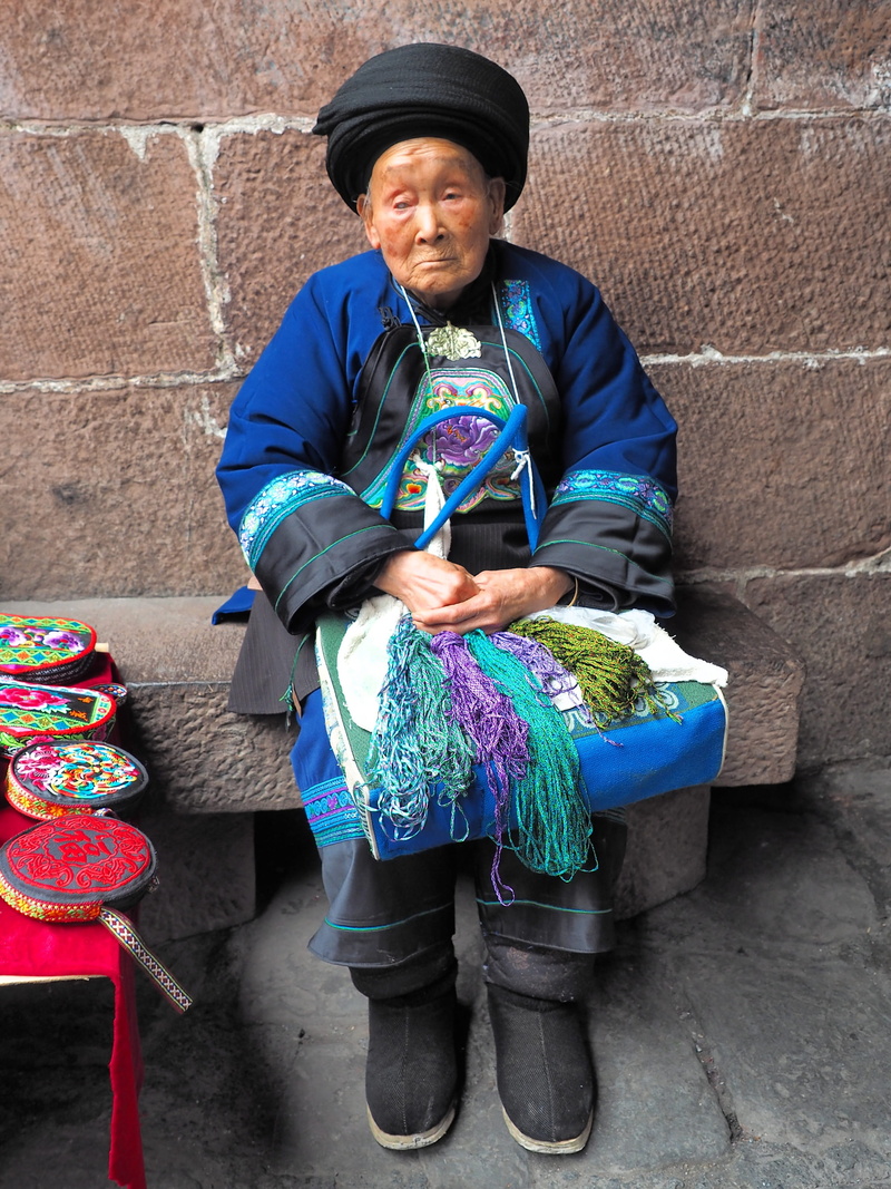fenghuang, outdoors, women, one person, holding, real people, hat, 90 years, senior adult, traditional clothing, leisure activity, ao, day, casual clothing
