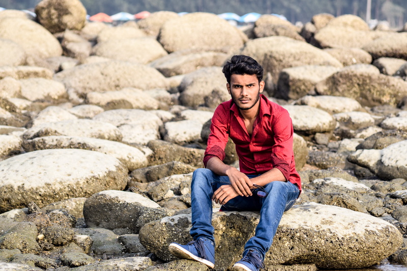 red, wear, rocks, gray, stones, blue, rock, portrait, solid, young adult, casual clothing, shirt, daylight, front view, one person, adult, person, stone