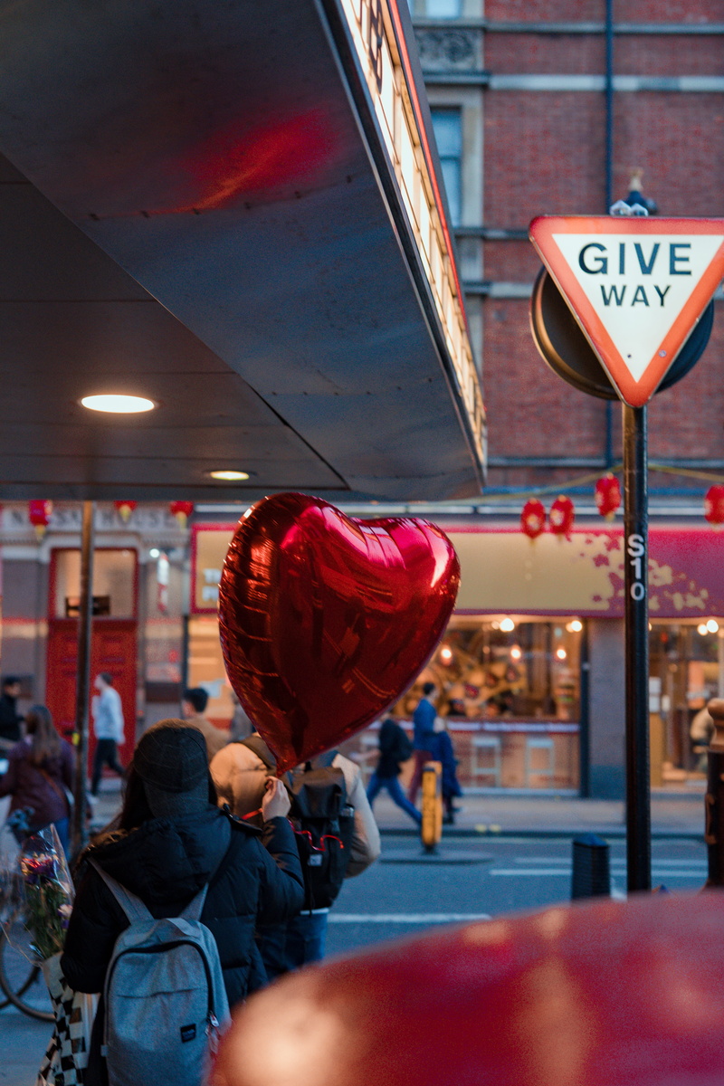 balloon, person, symbol, women, theme park, food, building exterior, incidental people, heart, text, road sign, transportation, meal, focus on foreground