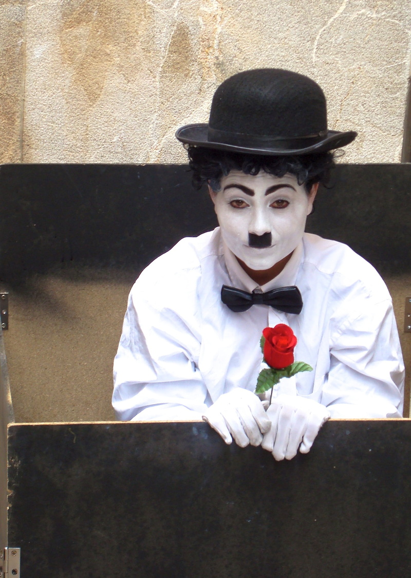 mask, dress, looking at camera, portrait, men, luggage, males, chaplin, waist up, rose, man, hat, holding, one person, makeup, shirt, face, uniform, wall - building feature