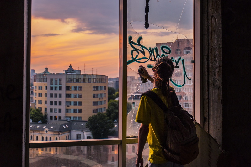 2K, architecture, side view, looking, broken, outdoors, built structure, contemplation, city life, one person, cityscape, bottle, graffiti, building, city