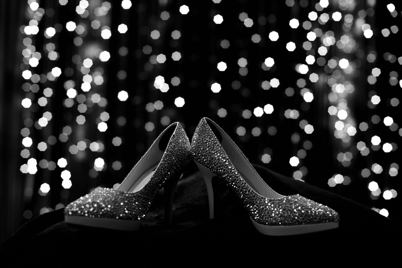 fashion, focus on foreground, shiny, one person, celebration, illuminated, close-up, 5K, stiletto, shoe, christmas lights, human leg, bokeh, black and white
