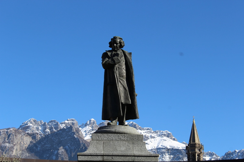 cold temperature, sky, sculpture, mountain range, human representation, art and craft, statue of antonio stoppani, clear sky, 5K, blue, lecco, male likeness