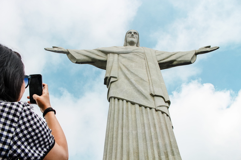 human, art and craft, person, rio, representation, cloud - sky, outdoors, redeemer, day, mobile phone, holding, sky, creativity, sculpture, nature, brazil