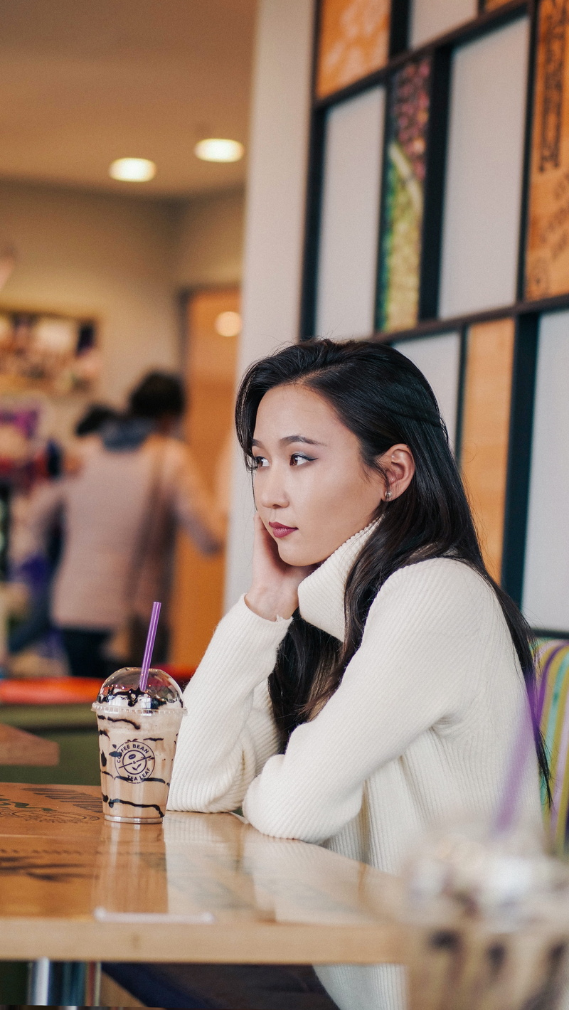 person, milkshake, one person, table, restaurant, young women, long hair, people, drink, hair, cafe, black hair, waist up, milk, food and drink, glass