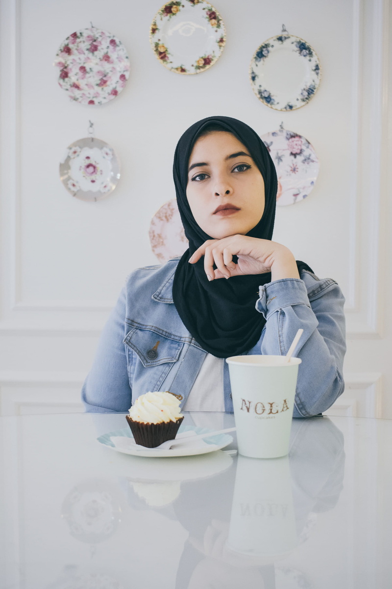 2K, looking at camera, front view, cake, flooring, indoors, wearing, hijab, home interior, dessert, cream, black, sweet, sweet food, person, headdress