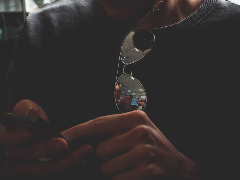 game, transparent, holding, digital, reflection, indoors, focus on foreground, body part, front view, sunglasses, 2K, beard, women, interface, experience