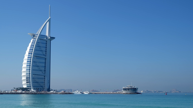 painted, nautical vessel, blue, mode of transportation, office building exterior, building exterior, burj al arab, water, white, skyscraper, sky, outdoors