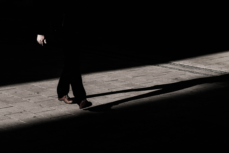 adult, stand, focus on shadow, sunlight, male, legs, pants, hand, nature, pathway, brick, footpath, human limb, wearing, black, walking, human leg, gray