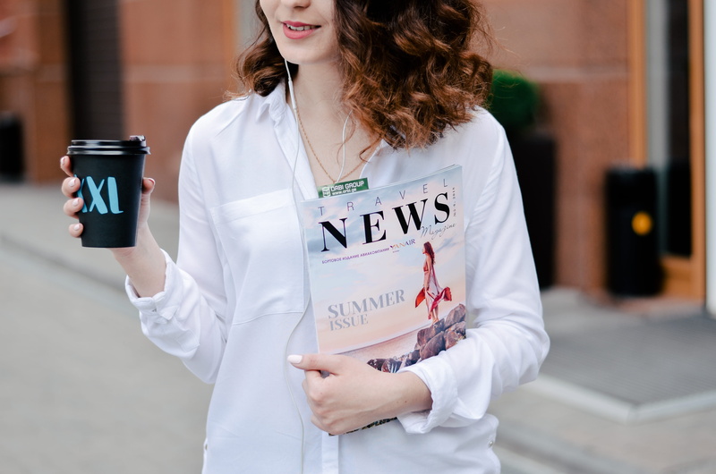 cup, focus on foreground, girl, text, lab coat, caucasian, hairstyle, reading, headphone, holding, happiness, young adult, takeaway, morning, waist up