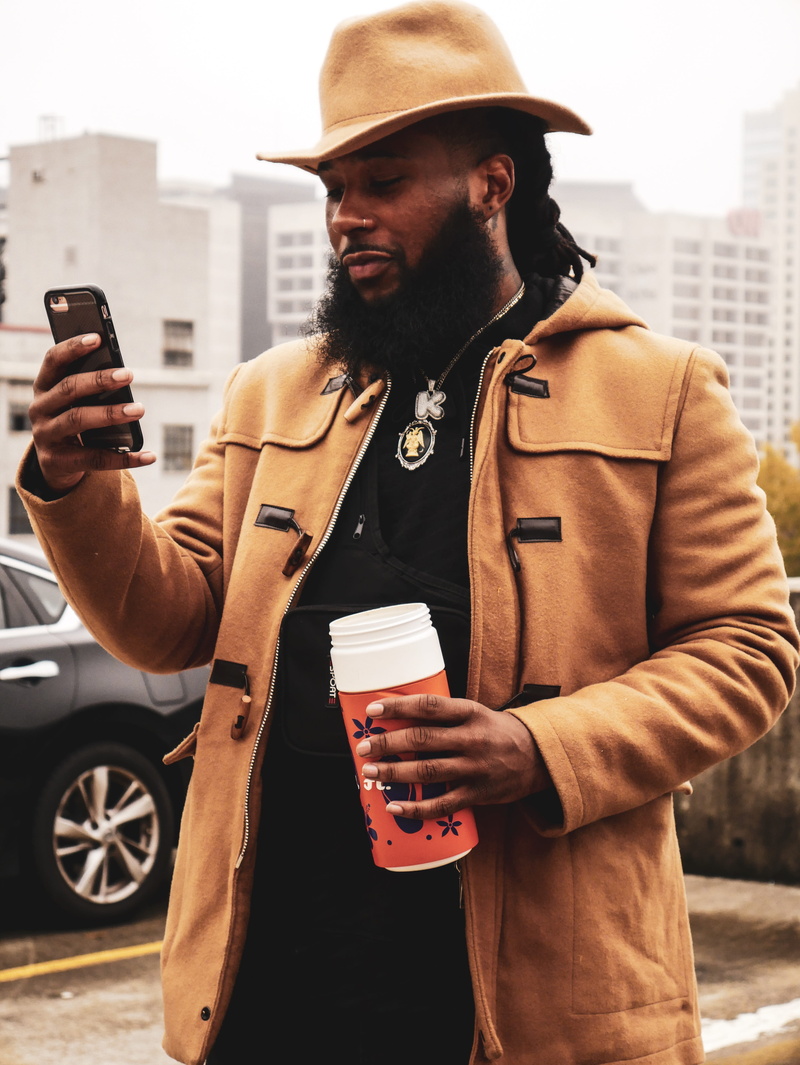 clothing, real people, waist up, front view, mobile phone, hat, communication, outdoors, outfit, wear, one person, lifestyles, smart phone, fashion, wireless technology