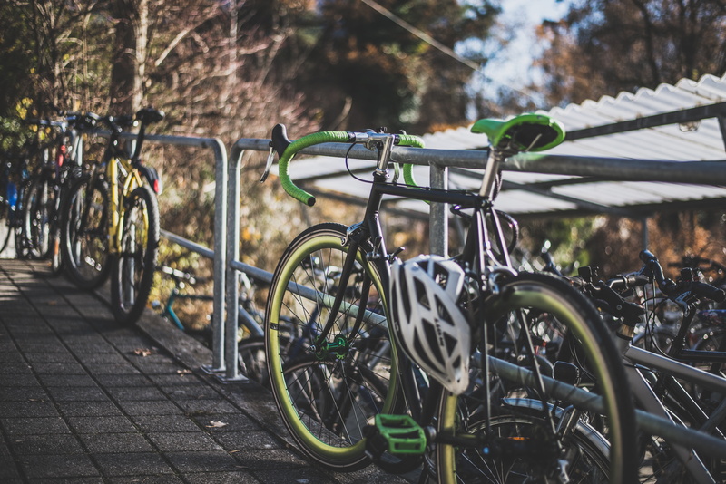 black, in a row, helmet, tree, footpath, parking, beside, green, street, mode of transport, nature, city, sport, outdoors, summer, parked, hobby, 5K, focus on foreground