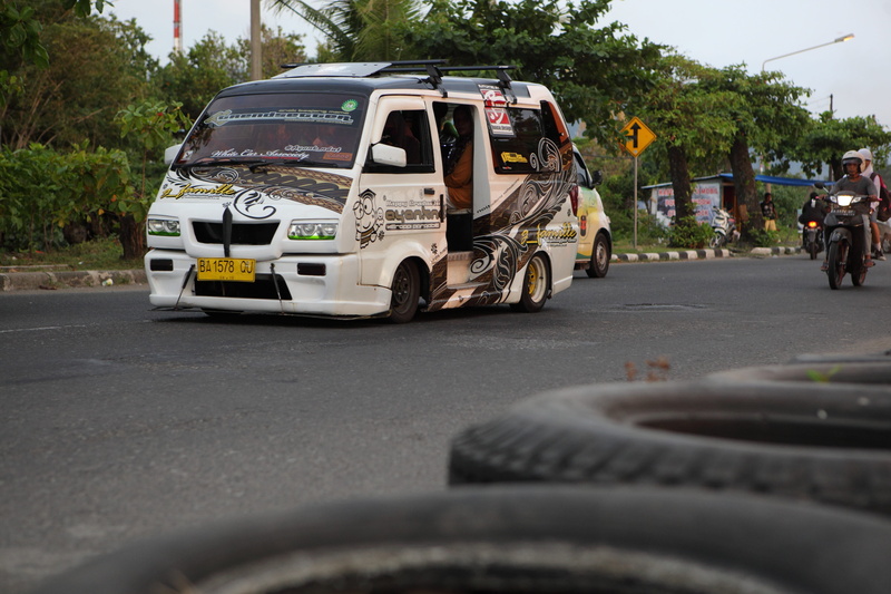 land vehicle, jinrikisha, tire, sign, mode of transportation, outdoors, padang, motor vehicle, traffic, city, incidental people, 5K, transportation, rickshaw