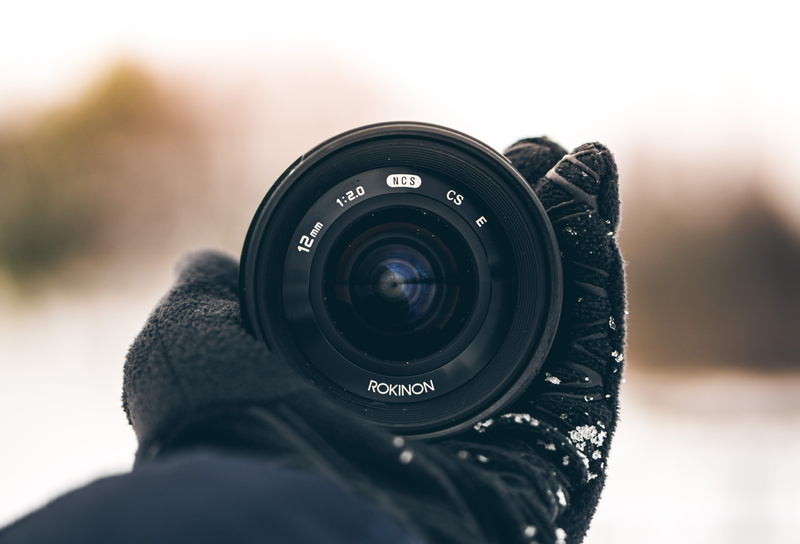 rokinon, selective focus, photographing, snow, digital camera, hand, pov, activity, photography themes, black color, focus on foreground, camera - photographic equipment