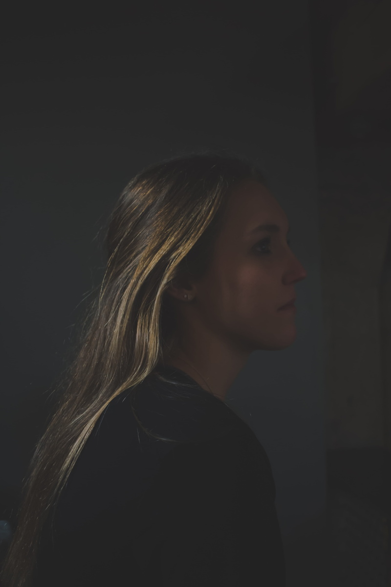 lifestyles, women, black, headshot, hair, profile view, young adult, hairstyle, looking, contemplation, black background, dark, sideview, indoors, chair