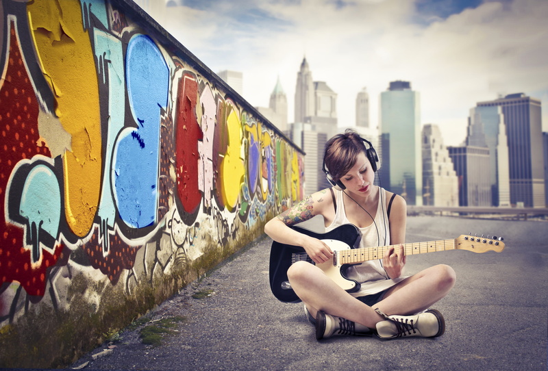 leisure activity, wall, sitting, full length, telecaster, young women, built structure, girl, the sky, black, graffiti, outdoors, the city, young adult