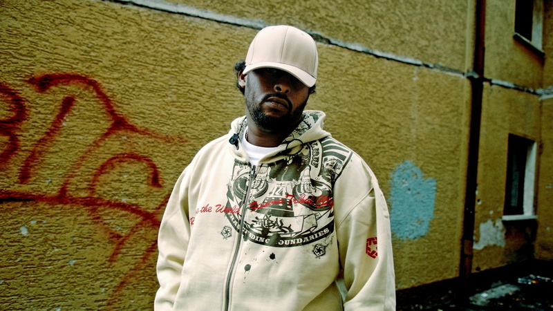 hoodie, day, gray, waist up, 1080P, standing, one Person, casual clothing, city, print, front view, males, graffiti, art and craft, building exterior