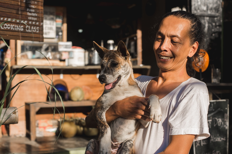 one animal, canine, females, domestic, pet owner, bali, one person, smile, on hands, domestic animals, balinese, positive emotion, real people, dog, mammal