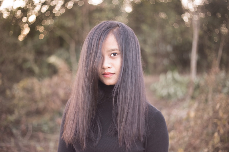 tribal girl, front view, standing, people, teenager, black hair, outdoors, portrait, focus on foreground, bangs, asian girl, waist up, hair, pretty, tree