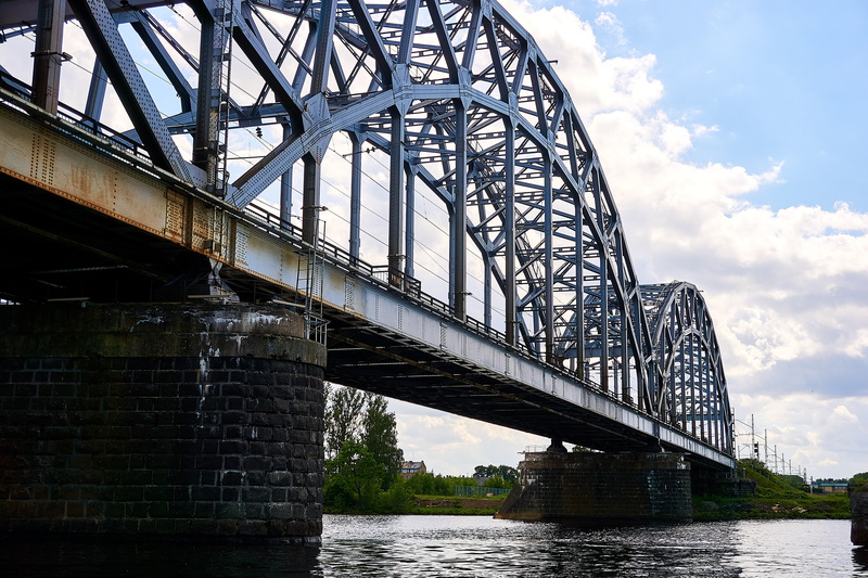 riga, transportation, water, architecture, industry, travel destinations, arch bridge, low angle view, cloud - sky, connection, waterfront, sky, outdoors