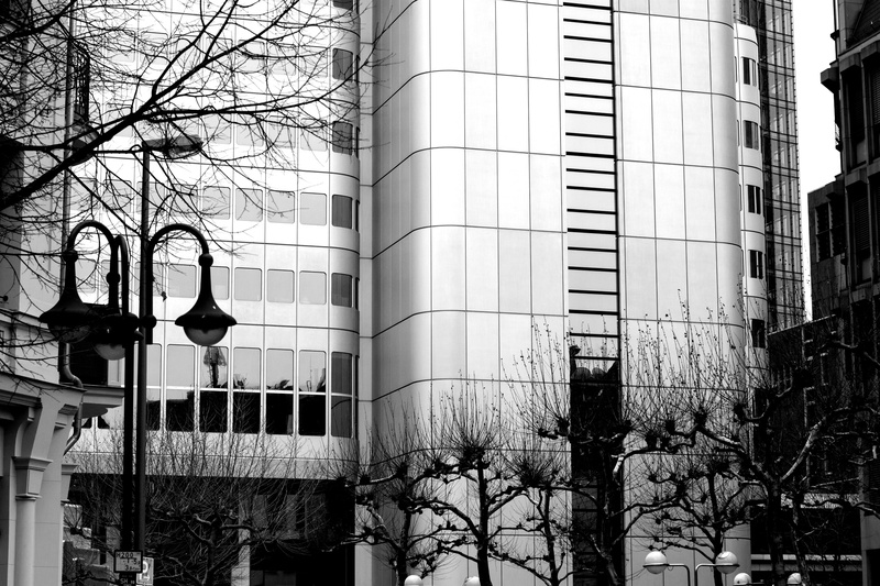 monochrome, building exterior, day, window, built structure, street light, grayscale, lighting equipment, glass, outdoors, office, skyscraper, low angle view