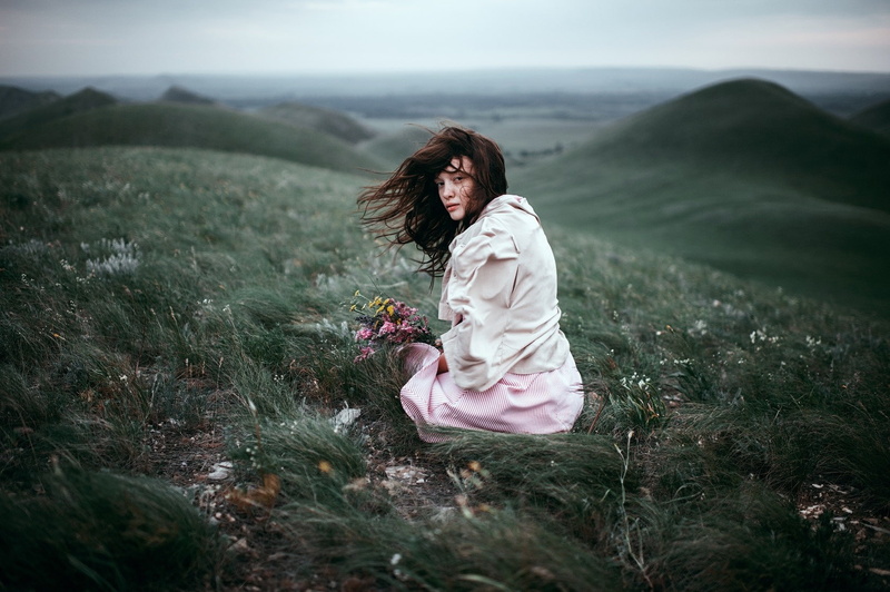 wind, land, long hair, beauty in nature, women, flowers, brown hair, young adult, adult, plant, hairstyle, sitting, tranquility, outdoors, women outdoors