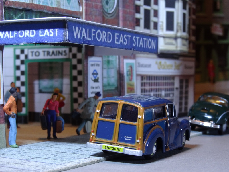 text, architecture, motor vehicle, city street, land vehicle, model car, incidental people, walford east station, car, diorama, model train, 5K, focus on foreground