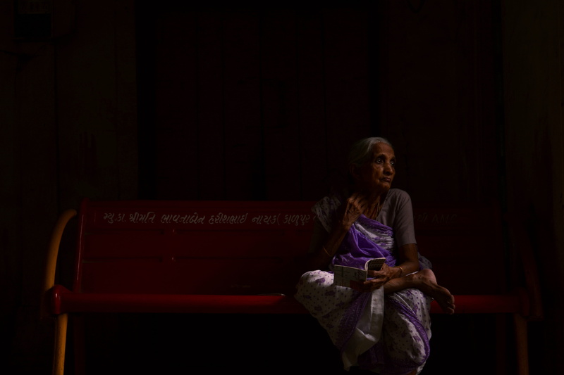 smiling, sitting, looking at camera, old, casual clothing, leisure activity, one person, ahmedabad, india, bench, seat, front view, emotion, black background