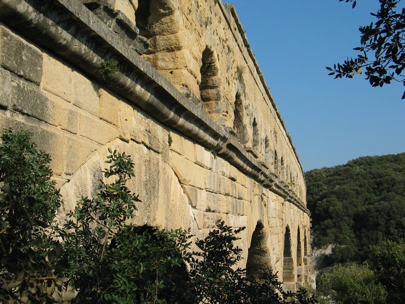 sky, outdoors, low angle view, architectural column, no people, travel destinations, pont du gard, building exterior, france, old, tree, nature, archaeology