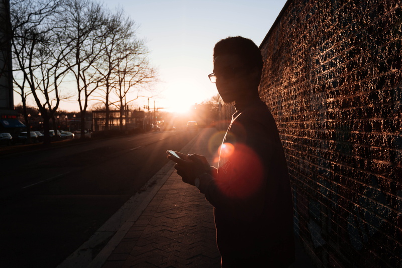 trees, smart phone, scenic, leisure activity, sunset, transportation, sunrays, eyewear, holding, wall, sideways, sunlight, environment, person, fashion