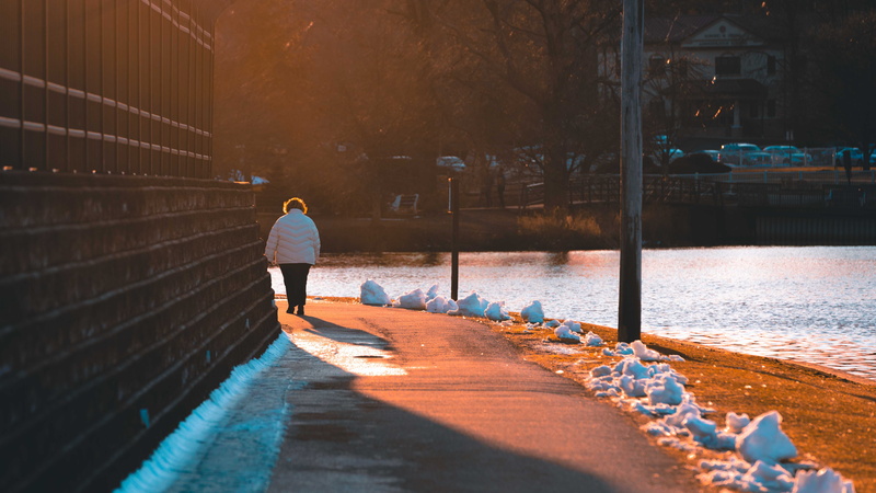 outdoors, overcoat, walkway, handrail, footpath, one person, walking, casual clothing, sidewalk, apparel, sunlight, along, pedestrian, dating, full length
