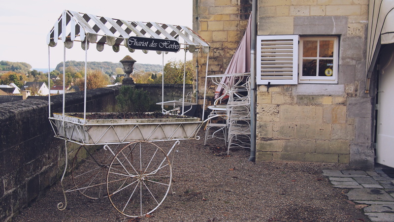 outdoors, day, plants, vintage, cart, 2K, building exterior, soil, text, chariot, architecture, residential district, building, table, window, no people