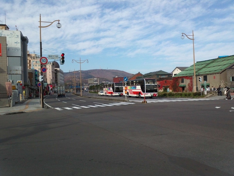 land vehicle, intersection, cloud - sky, building, sign, street, street light, otaru, incidental people, road, built structure, 2K, nature, mountain, day